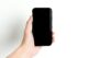 Simple image of a hand holding a black smartphone with a white background, emphasizing minimalism and technology.